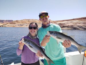 A couple from Boston hold up thier catches and smile broadly, they are fishing with Captain Bill of Ambassador Guides on Lake Powell, AZ
